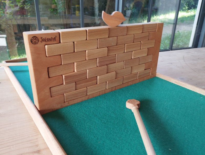 jeu du muret: un oiseau est posé sur un mur de blocs de bois.